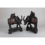 A pair of carved wood models of water buffalo each mounted with a figure 27cm high