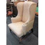 A wing back armchair with damask upholstery on square chamfered legs and castors