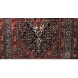 A Persian rug, red ground, central floral medallion within multiple borders, with label faintly