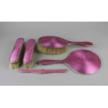 A George V silver five piece silver and pink guilloche enamel dressing table set, (marks worn)