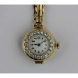 A gold and diamond set circular cased lady's wristwatch with a jewelled lever movement the enamel