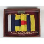 A framed Naval pennant with plaque inscribed 'To Commander B J Adams from the Warrant Officers and