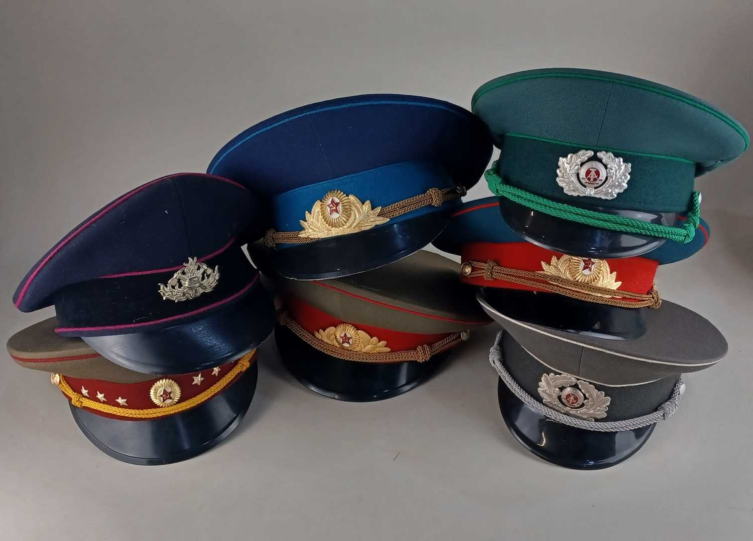 A collection of replica military hats to include East German Army guard, and Soviet Air Force