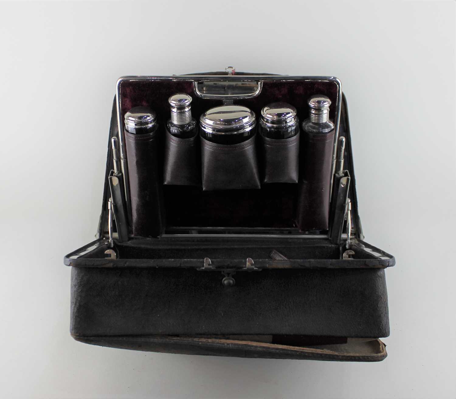 A gentleman's travel dressing case with fitted interior containing chrome topped glass jars, mirror,