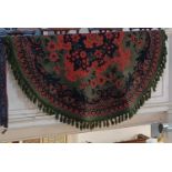 A green circular rug with red and black floral decoration approx 194cm