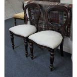 A pair of Victorian style balloon back dining chairs with cream upholstered seats on baluster legs