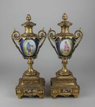 A pair of Sevres style gilt metal and porcelain garniture vases, each decorated with an oval panel