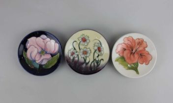 Three Moorcroft pottery trinket dishes; to include Magnolia and Hibiscus patterns