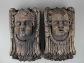 A pair of carved oak cherub mounts, by repute from The Old Vicarage Goodrich, Herefordshire, 35cm by