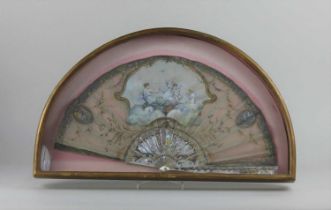 A framed painted and sequinned fan decorated with a classical figure, birds and cherubs, the