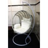A white rattan swing basket egg chair on metal stand