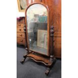 A Victorian mahogany cheval mirror the arched mirror plate in a moulded frame flanked by turned