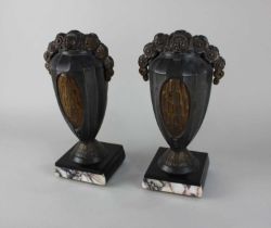 A pair of Art Deco patinated metal clock garniture vase ornaments, both with floral surmount, on