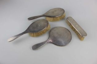 A George V silver dressing table set three brushes and a hand mirror with a simple line pattern