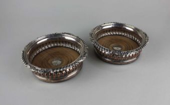 A pair of 19th century silver plated wine coasters with gadrooned borders, turned wood bases with
