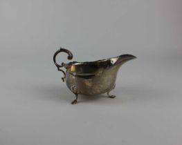 An Edward VII silver sauce boat with flying scroll handle on shell cast hoofed feet, maker William