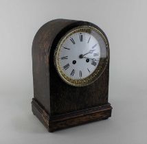 An oak mantle clock domed case with circular white enamel dial and Roman numerals, striking on a