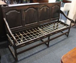 A 19th century oak settle with four panelled back and string seat with open scroll arms on turned