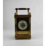 A gilt metal cased carriage clock, the architectural case with bevelled glass panels, white enamel