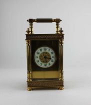 A gilt metal cased carriage clock, the architectural case with bevelled glass panels, white enamel