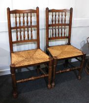 A pair of spindle back dining / side chairs with rush seat on hoof front feet with turned front