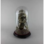 A brass skeleton clock with fusee movement, under a glass dome clock 29cm high, with key