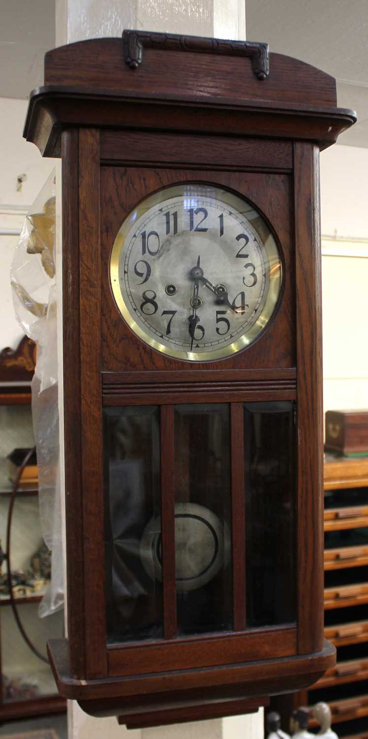 An early 20th century oak cased wall clock 81cm high, with pendulum and key
