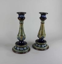 A pair of Royal Doulton glazed stoneware candlesticks decorated with flowers and foliage in blue,