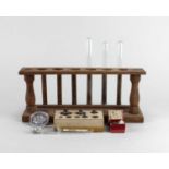 A wooden test tube rack and three glass test tubes, a small box of 1/4 oz micro circles, a small