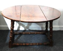 A small oak drop leaf side table, with oval swivel top on turned legs with low supporting