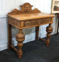 A Victorian carved oak side table with raised back and drawer with carved central lion head and