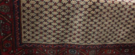 A Persian type rug, red ground, with red and beige floral lattice pattern within multiple borders