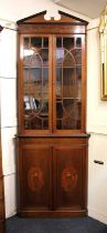 An Edwardian Sheraton style inlaid mahogany corner cupboard the top with broken arch cornice, two