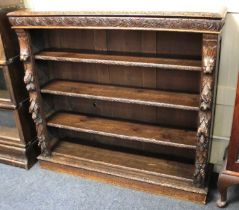 A Victorian carved oak bookcase with three shelves and deeply carved fruiting pines and lion mask