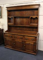 A George III style oak dresser with dentil cornice over enclosed plate rack with two shelves and two