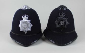 Two policeman's helmets bearing badges for Cornwall and Bedfordshire Constabularies