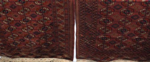 A pair of Turkoman rugs, red ground, with repeating gul design, both with label verso 'Kiskan