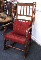 An oak rocking chair with slatted back, turned side rails and upholstered seat