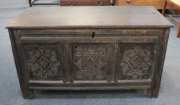 An 18th century oak coffer, with rectangular hinged top and carved three panel front, on stile