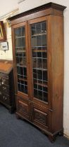 An early 20th century cabinet bookcase with two lead glazed panel doors enclosing four shelves,