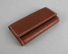 A Rolex brown leather key case, the embossed case with repeat 'Rolex' lettering design, in