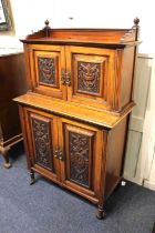 An early 20th century carved cabinet, with two panel doors enclosing cupboard and two small drawers,