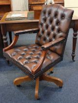 A brown leather upholstered revolving office chair with button back and seat on four outswept legs