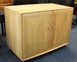 A contemporary Ercol side cabinet with two cupboard doors enclosing sliding shelf and compartment,