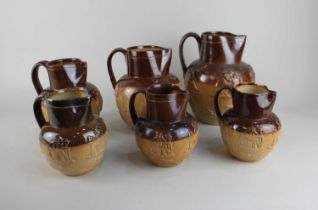 A collection of Doulton Lambeth glazed stoneware graduated jugs with the Harvest design, one with