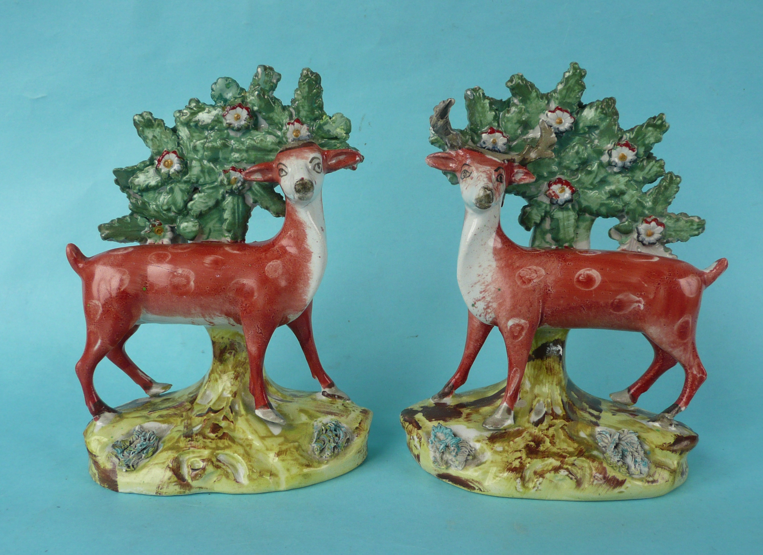 A pair of Staffordshire figures of deer depicted standing before a bocage on well painted bases