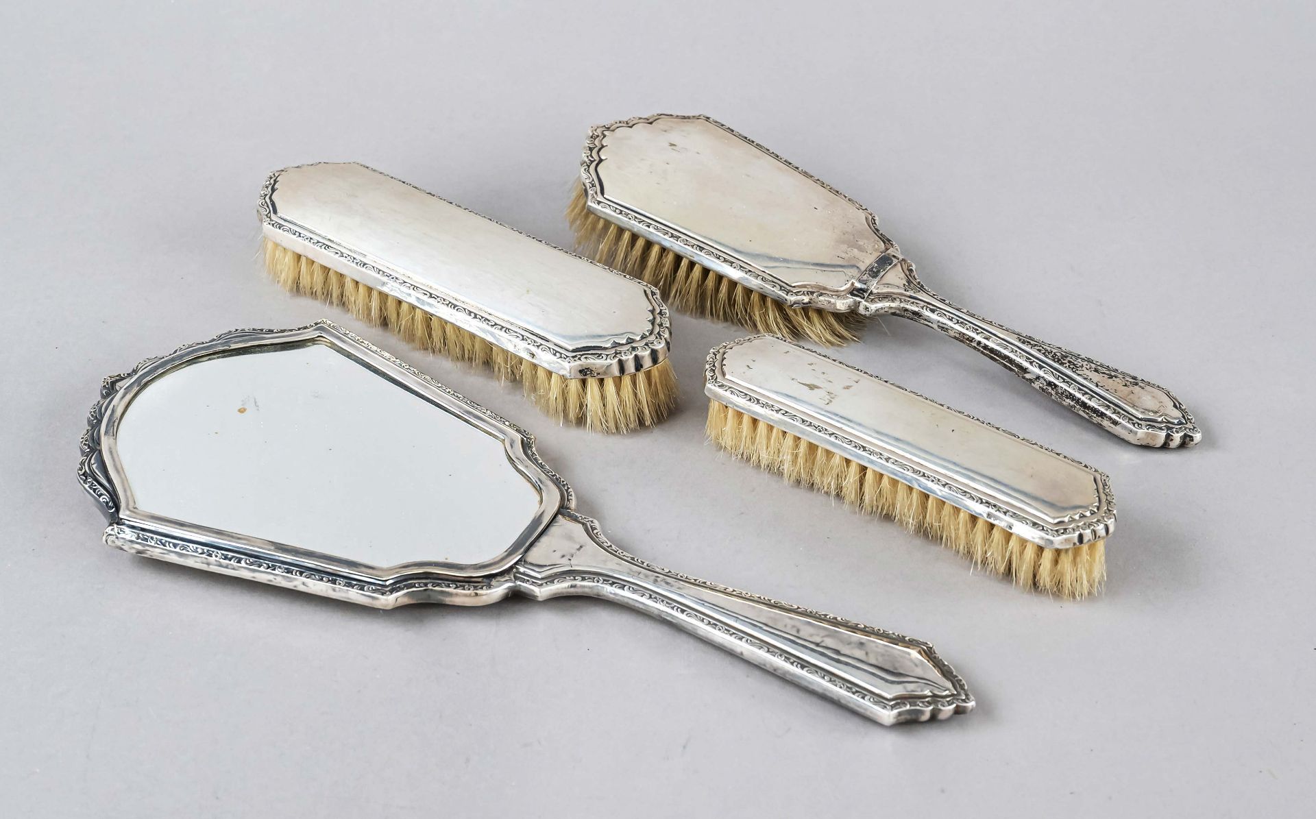 Four-piece hairdressing set, early 20th c., silver 800/000, each with relief decor rim, 3 brushes