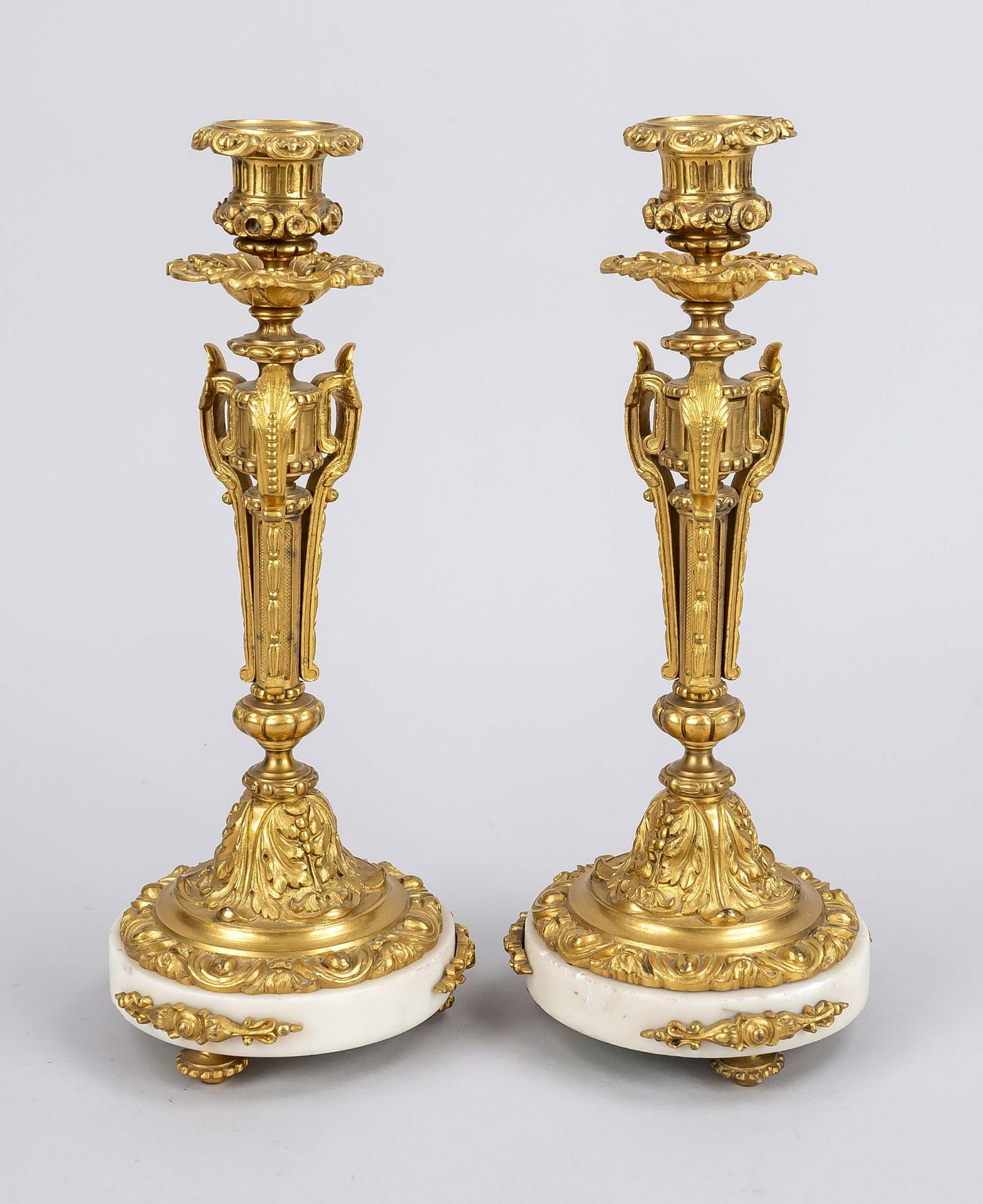 Pair of candlesticks, 19th/20th c., gilded bronze, white marble. Round marble plinth on 3 feet,