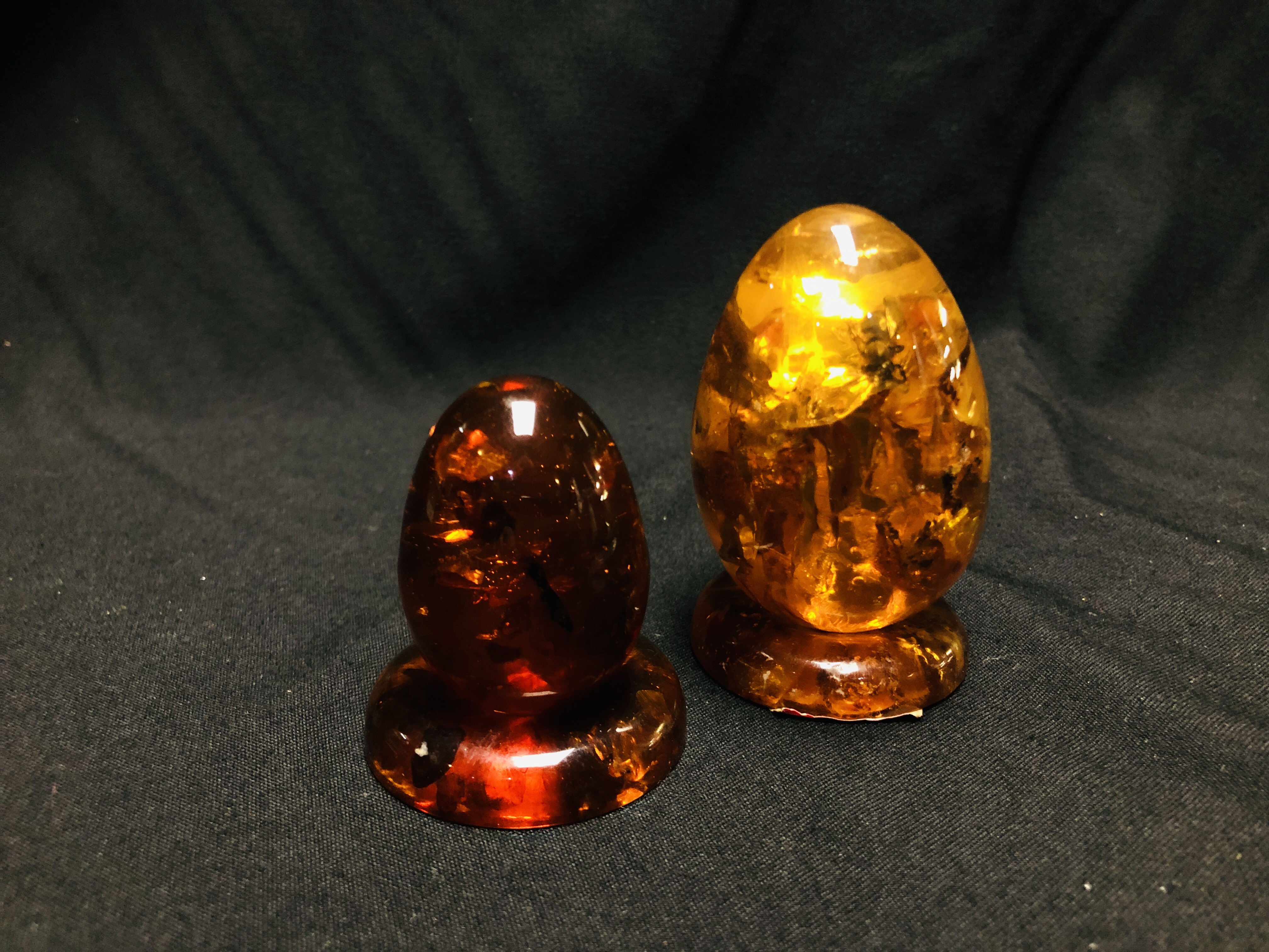 TWO POLISHED EGGS, ONE HAVING INSET INSECT ALONG WITH TWO POLISHED AMBER DISCS, DIAMETER 4.5CM.
