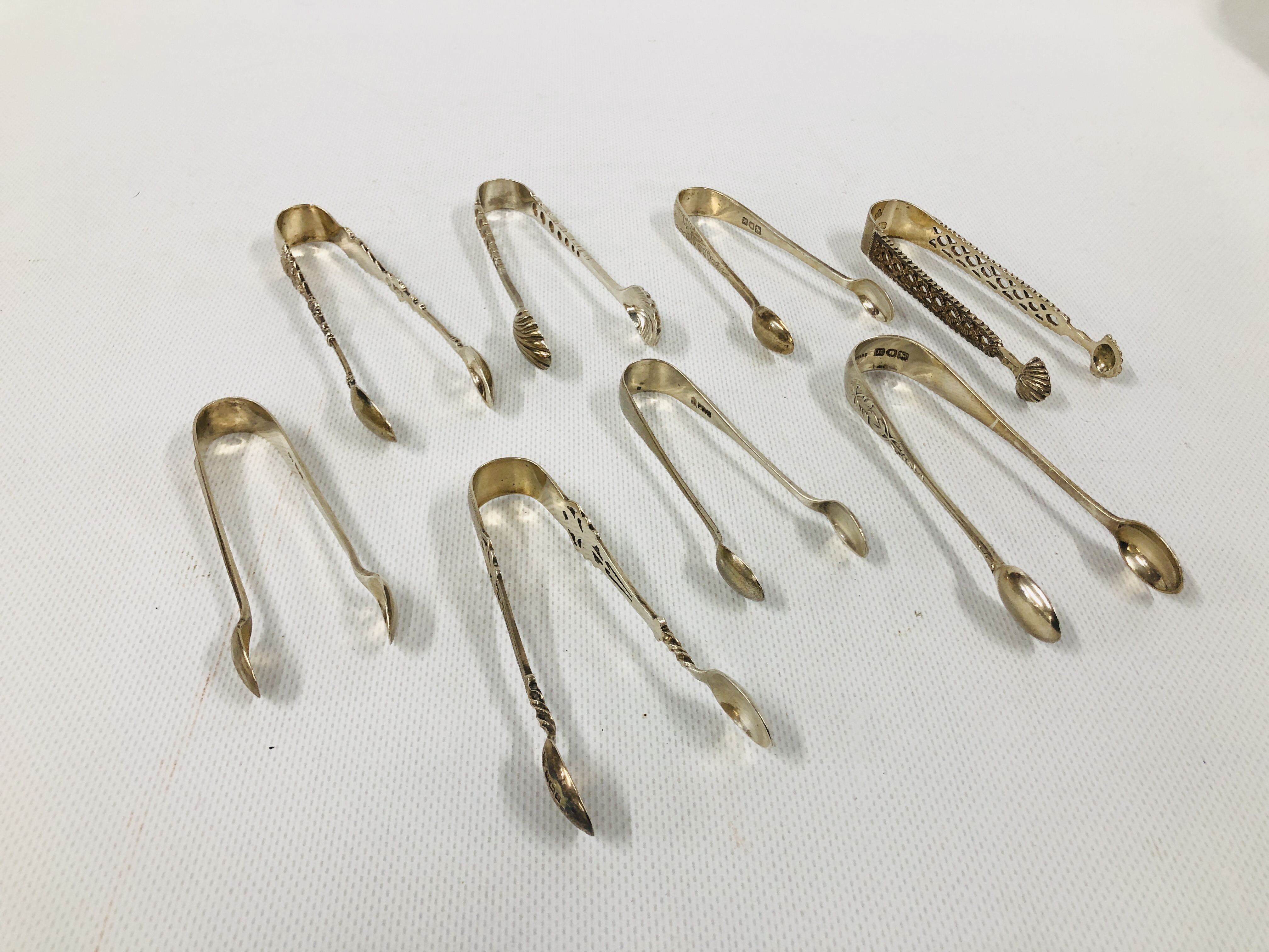 GROUP OF 8 VARIOUS SILVER SUGAR NIPS INCLUDING A PIERCED EXAMPLE, VARIOUS MAKERS AND ASSAYS.